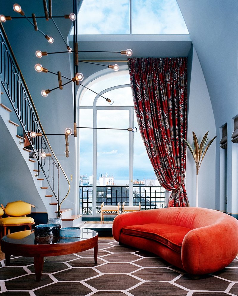 Chic Parisian LR with orange sofa and print draperies